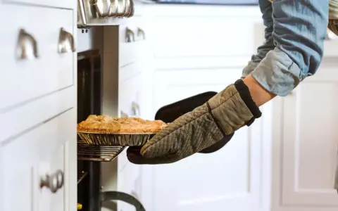 Persona saca un pastel del horno con guantes de cocina personalizados.