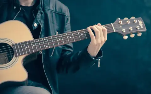 Mężczyzna w skórzanej kurtce gra na gitarze. Akordy układają się w piękną tonację d dur, tworząc melodyjną opowieść.