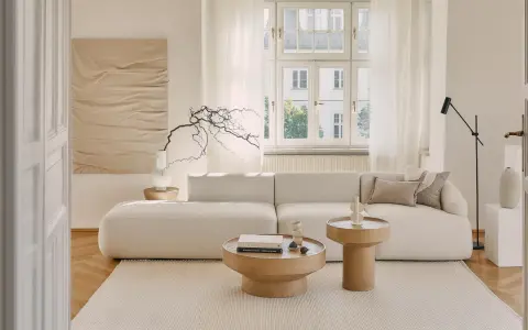 Jasny salon z sofą i stolikami kawowymi w odcieniach beżu i bieli. Kolor ecru jaki to kolor? To subtelność i spokój.