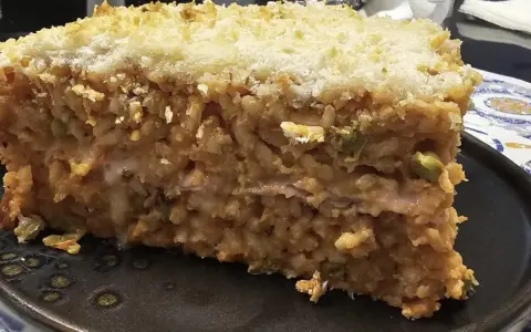 Una fetta di riso al forno, stratificato e dorato, con una crosta croccante di pangrattato.