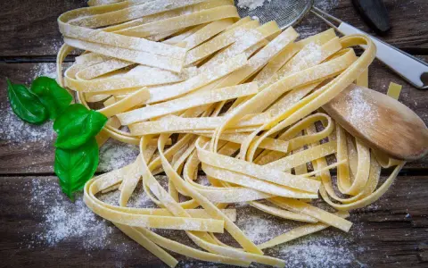 Świeży makaron bezglutenowy, posypany mąką, z listkami bazylii. Idealny przepis na domowy makaron.
