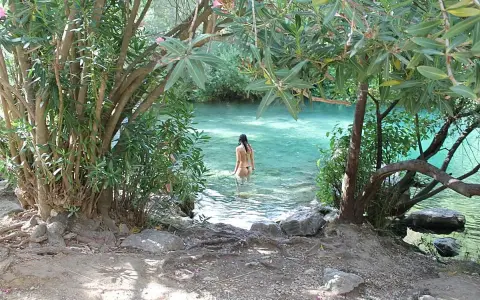Una mujer se baña en la cueva del gato, un oasis de aguas cristalinas rodeado de vegetación exuberante.