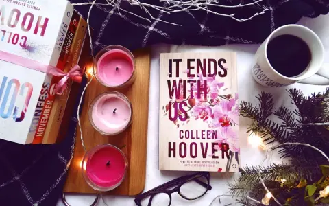 Książka "It Ends With Us" Colleen Hoover, obok świec, kawy i innych książek, tworzy przytulną atmosferę do czytania.