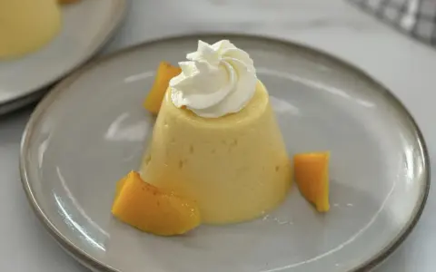 Postre de melocotón en almíbar con crema batida y trozos de melocotón.