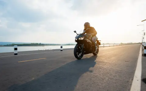 Motocyklista przemierza malownicze trasy motocyklowe pomorskie w blasku zachodzącego słońca.