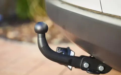 Gancio traino nero montato sul paraurti di un'auto, pronto per il traino secondo il codice della strada.