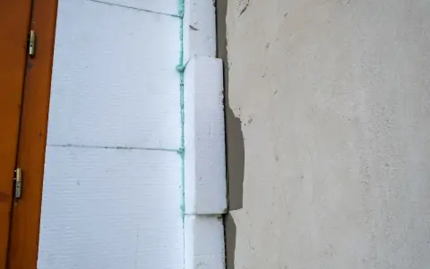 Izolacja styropianowa przy drzwiach, z pianką i narożnikami do elewacji.