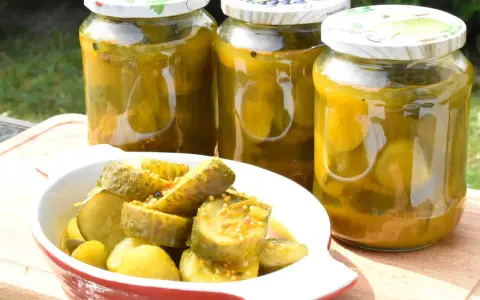 Słoiki z ogórkami z curry i miseczka z pokrojonymi ogórkami. Idealne na letnie przetwory.