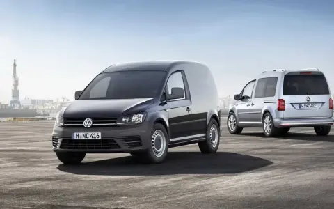 Dos furgonetas Volkswagen Caddy, una negra y otra plateada, demuestran su versatilidad como vehículo mixto adaptable en un entorno portuario.