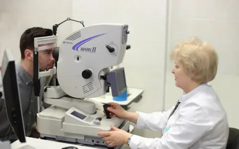Lekarz wykonuje badanie wzroku pacjentowi na nowoczesnym sprzęcie. Przed badaniem angiografia fluoresceinowa przeciwwskazania są kluczowe.