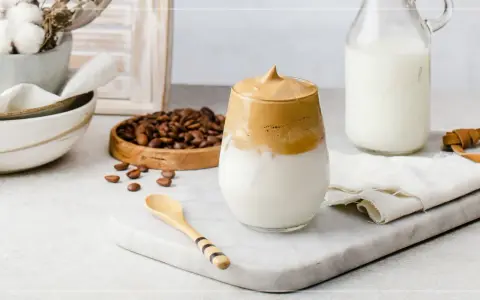 En krämig dalgona coffee med fluffigt skum, serverad med mjölk och kaffebönor.