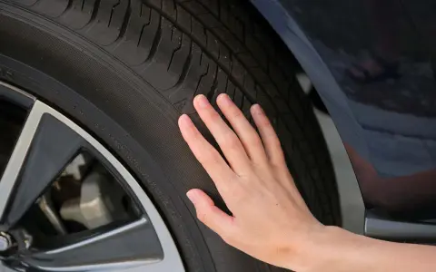 Una mano toca la banda de rodadura de un neumático, sugiriendo la pregunta de cuánto duran las ruedas de un coche.
