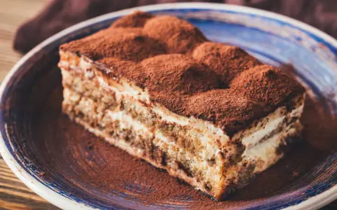 Une part de tiramisu onctueux, saupoudrée de cacao, prête à être dégustée. Une recette gourmande pour le plaisir.