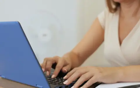 Kobieta pisze na laptopie, tworząc idealny profil. Zastanawiasz się, jakie rzeczy o których kłamiemy na portalach randkowych ukrywa?