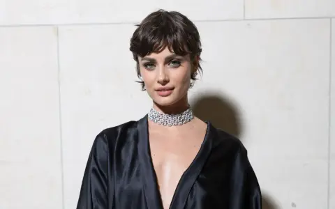 Frau mit einer modernen Frisur zwischen Pixie und Bob, trägt ein schwarzes Seidenkleid und einen funkelnden Choker.