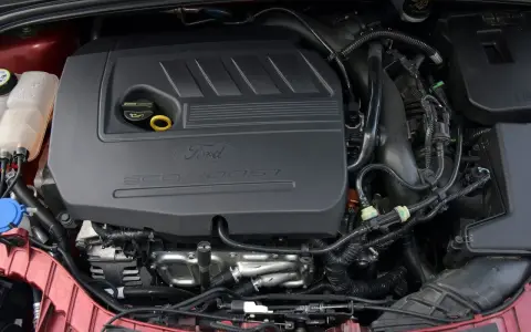 Silniki Ford Focus MK3 EcoBoost. Widok komory silnika z widocznym czarnym plastikowym elementem z napisem "Ford EcoBoost".