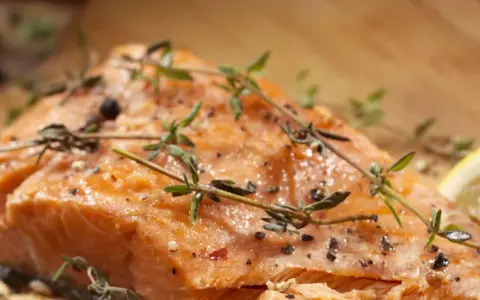 Delicioso salmón al horno, jugoso y dorado, con hierbas frescas y pimienta.