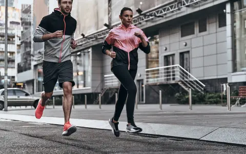 Coppia in corsa running in città, con abbigliamento sportivo colorato.