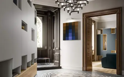 Ingresso con armadiature moderne, lampadario geometrico e un quadro astratto, in un ambiente che evoca lo stile liberty moderno.