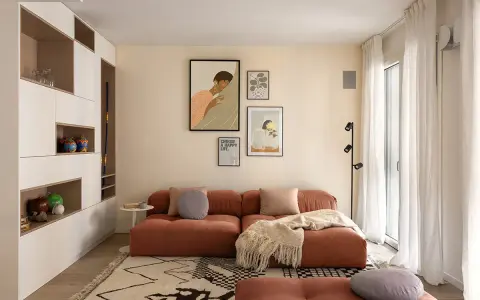 Un soggiorno moderno con divano color terracotta e tappeto geometrico. L'arredamento è pensato per abbinare tappeto e divano, creando un ambiente accogliente.