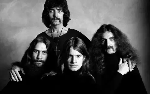 Czarno-białe zdjęcie zespołu Black Sabbath. Czterech mężczyzn z charakterystycznymi fryzurami i wąsami pozuje do portretu.