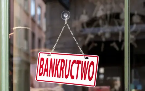 Tabliczka "BANKRUCTWO" wisząca na łańcuszku na szybie.