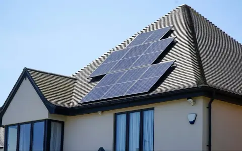 Panele fotowoltaiczne na dachu domu, działające jako agregator energii, łapią promienie słoneczne.