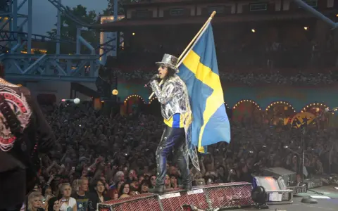 Alice Cooper i Sverige, med svensk flagga och en stor publik som filmar.