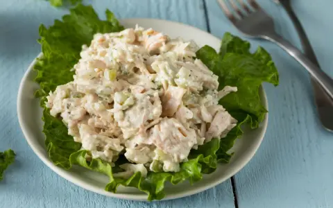 Un piatto di insalata di pollo della nonna, cremosa e ricca, servita su foglie di lattuga croccante.