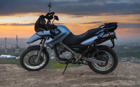 Niebieski motocykl BMW na wzgórzu, gotowy do podróży po Litwie, gdzie obowiązują ograniczenia prędkości.