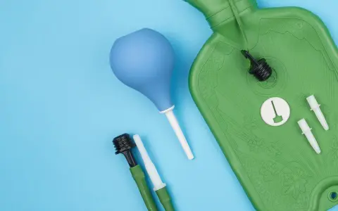 Grüne Spülflasche, blauer Birnensauger und Zubehör für die darmspiegelung vorbereitung auf blauem Hintergrund.