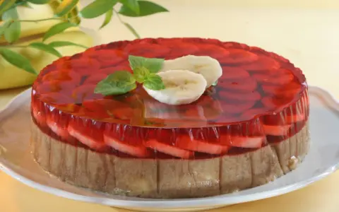 Kolorowe ciasto bananowe z galaretką na biszkopcie, ozdobione plasterkami banana i miętą.