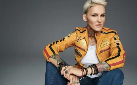 Agnieszka Chylińska w żółtej kurtce motocyklowej, z tatuażami i biżuterią. Jakby mówiła: "kiedyś do ciebie wrócę".