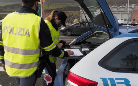Agenti della Polizia Stradale controllano documenti, forse per un caso di targa clonata, durante un posto di blocco.