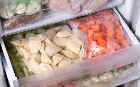 Zamrożone pierogi i warzywa w woreczkach w zamrażarce.