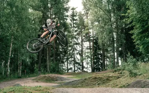 Mountainbike-åkare flyger genom luften i en skogspark nära Stockholm.