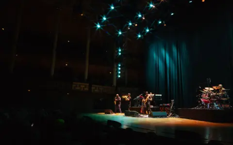 En jazzgrupp spelar på en scen under Stockholm Jazz Festival. Ljusen lyser upp scenen och publiken sitter i mörkret.