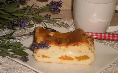 Pyszny sernik z brzoskwiniami, udekorowany gałązką lawendy, czeka na kawę.
