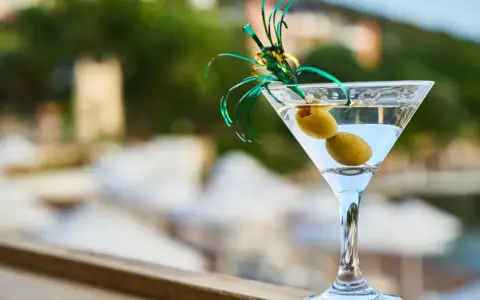 Elegancki kieliszek martini z dwiema oliwkami i zieloną ozdobą. Idealny na toast "cin cin fiero" w letni wieczór.