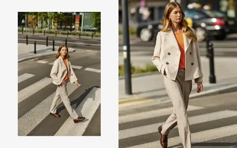 Elegancka stylizacja: jaka marynarka do beżowych spodni? Modelka w beżowej marynarce dwurzędowej i spodniach w prążek na pasach.