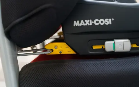 System Isofix co to? Widok z bliska na żółte zaczepy fotelika samochodowego Maxi-Cosi wpięte w mocowania Isofix.