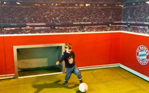 Kleiner Junge feiert seinen Allianz Arena Kindergeburtstag und kickt im FC Bayern Trikot.