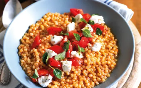 Fregola sarda ricetta originale: pasta tostata con pomodorini freschi, mozzarella e basilico, un piatto estivo profumato.