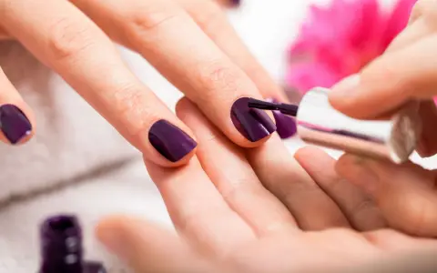 Applicazione smalto viola su unghie. Scopri come usare la fibra di vetro per unghie per un look impeccabile.