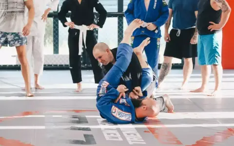 Dwóch mężczyzn w niebieskich kimonach ćwiczy chwyty na macie. To właśnie bjj co to za sztuka walki, która uczy kontroli i poddań.