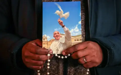 Dłonie trzymają obrazek z Papieżem Franciszkiem wypuszczającym gołębicę. To inspiracja z cytatów papieża franciszka.