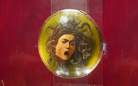 Przerażająca Meduza Caravaggia na okrągłej tarczy, z wężami zamiast włosów i wykrzywioną w krzyku twarzą.