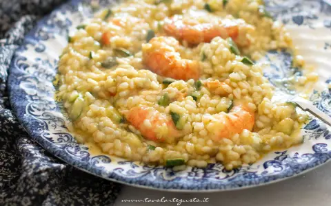 Risotto cremoso con zucchine e gamberetti, un piatto estivo da gustare.