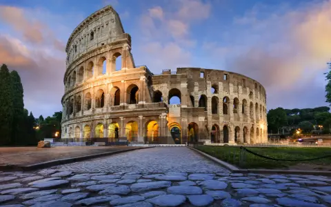 Il Colosseo, uno dei monumenti famosi a Roma, illuminato al tramonto con un cielo nuvoloso.