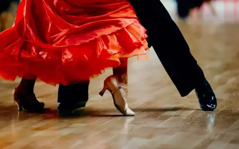 Para tańczy paso doble w rytm muzyki. Czerwona sukienka wiruje, a eleganckie buty poruszają się po parkiecie.